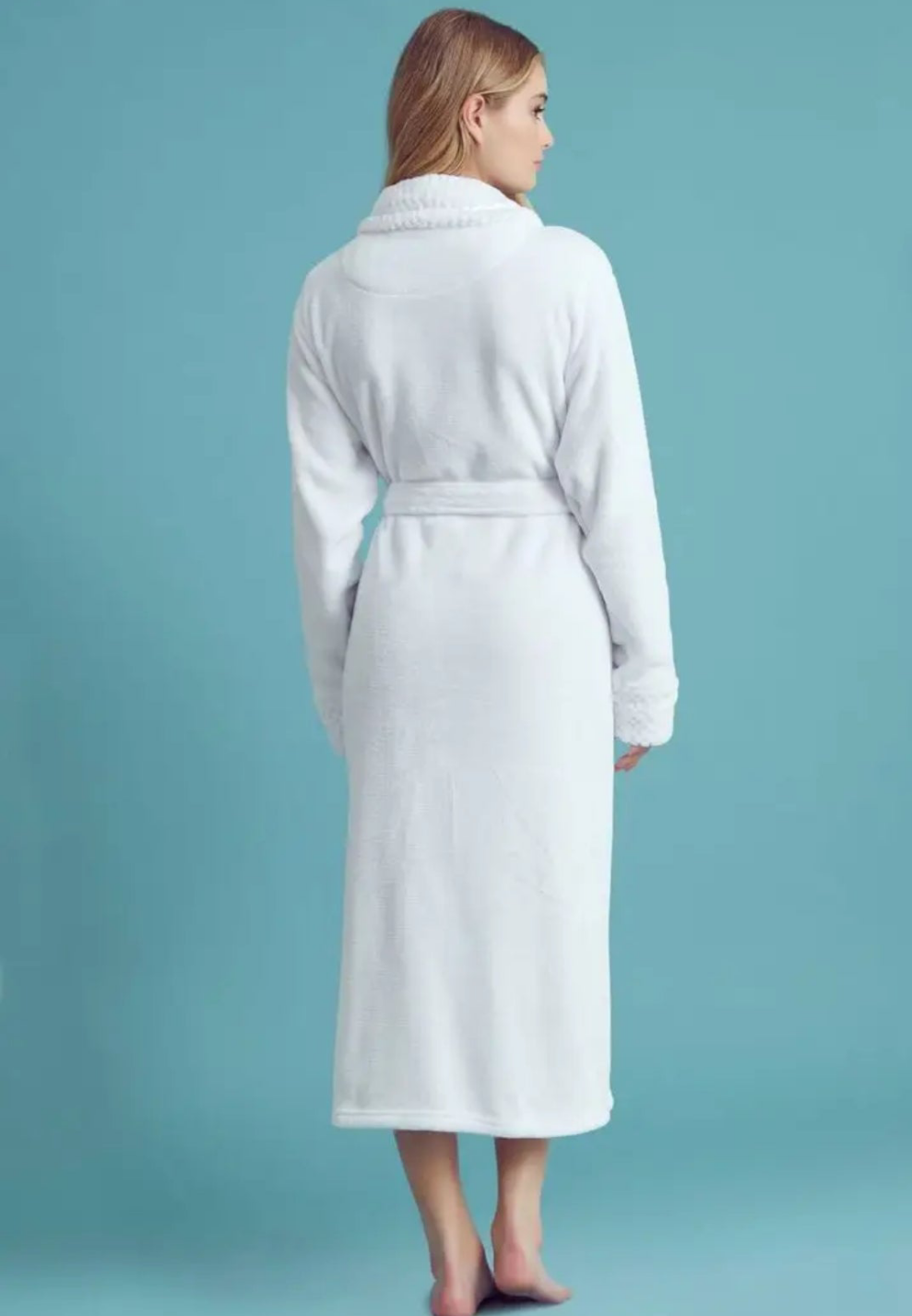 Woman wearing a white robe against a solid blue background