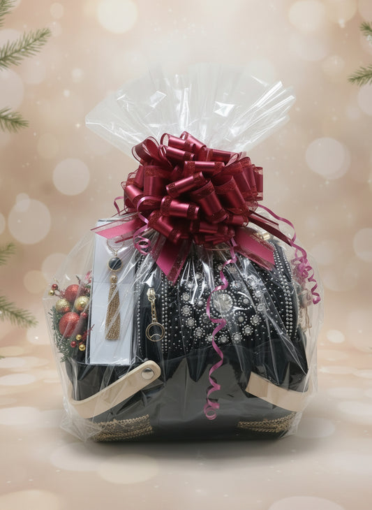 Gift basket with black purse and accessories wrapped in clear cellophane with a red bow on a beige background.