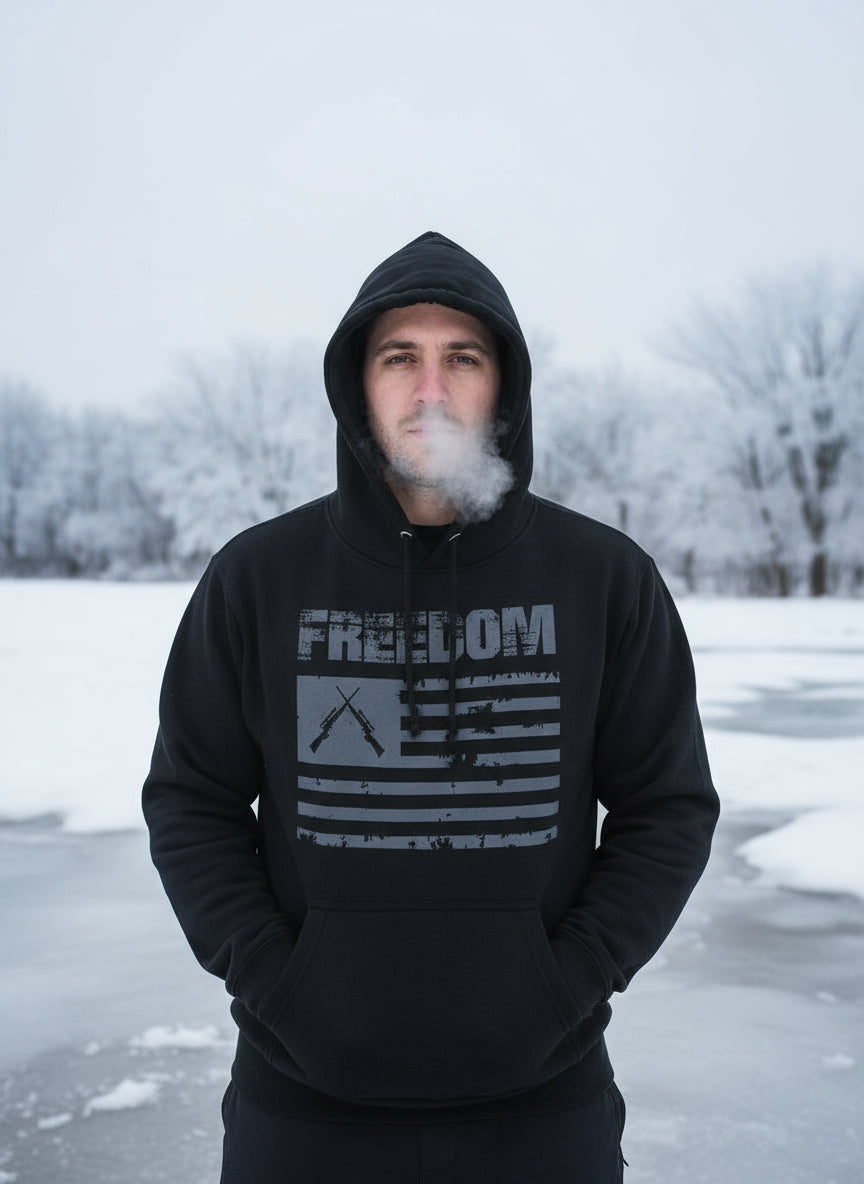 Person wearing a black hoodie with 'FREEDOM' and an American flag design, standing in a snowy landscape.