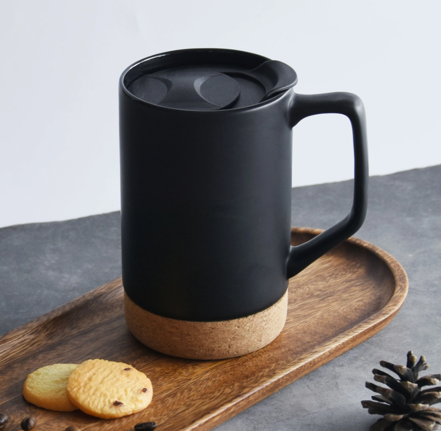 Black mug with cork base on a wooden tray with cookies