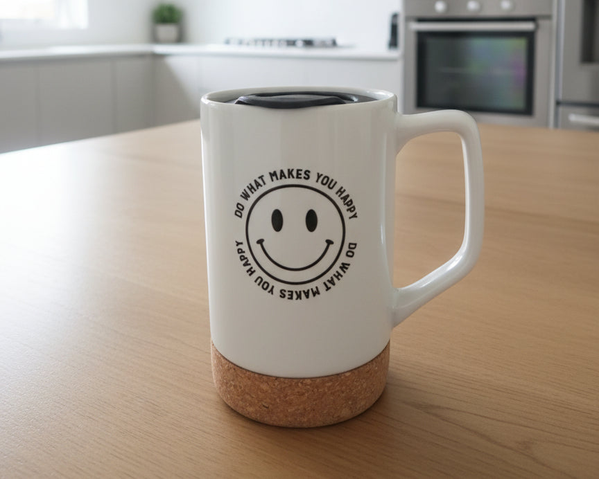 White mug with cork base and smiley face design on a wooden table