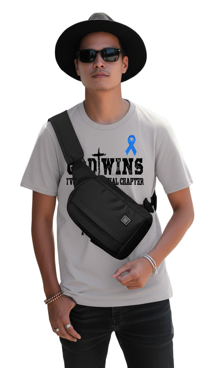 Man wearing a t-shirt with a blue ribbon design and carrying a black crossbody bag on a city street.
