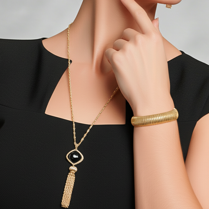 Woman wearing gold necklace, earrings, and bracelet against a gray background