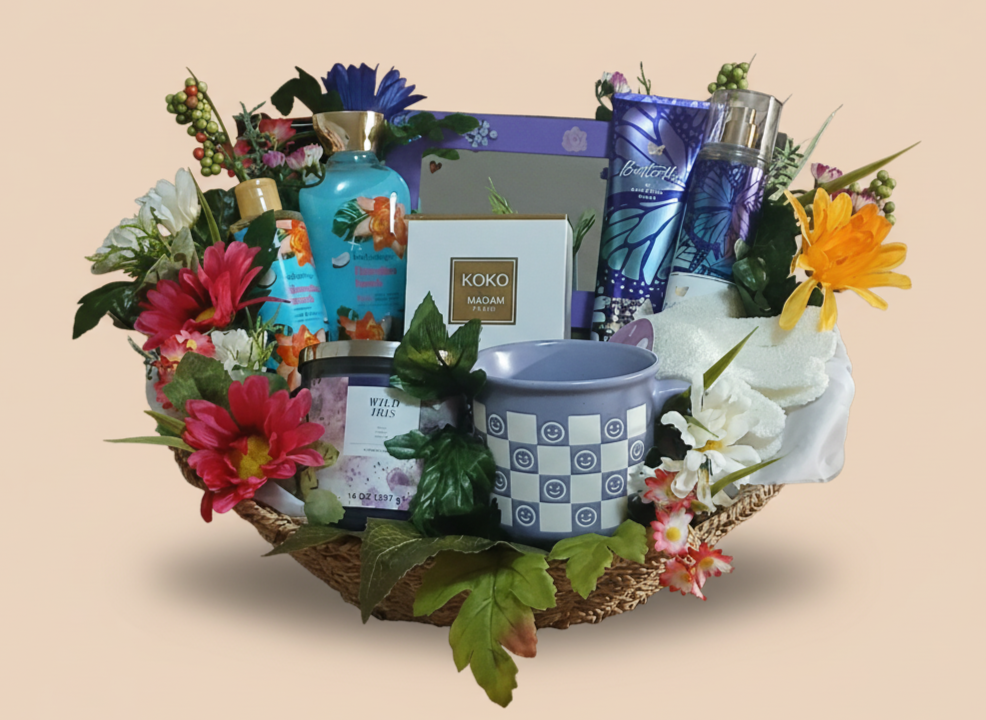 Gift basket with flowers, bottles, and a mug on a beige background
