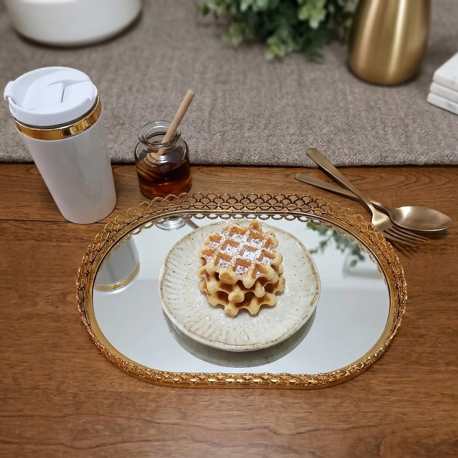 Waffle on a plate with a mirror, cup, and honey jar on a wooden table.