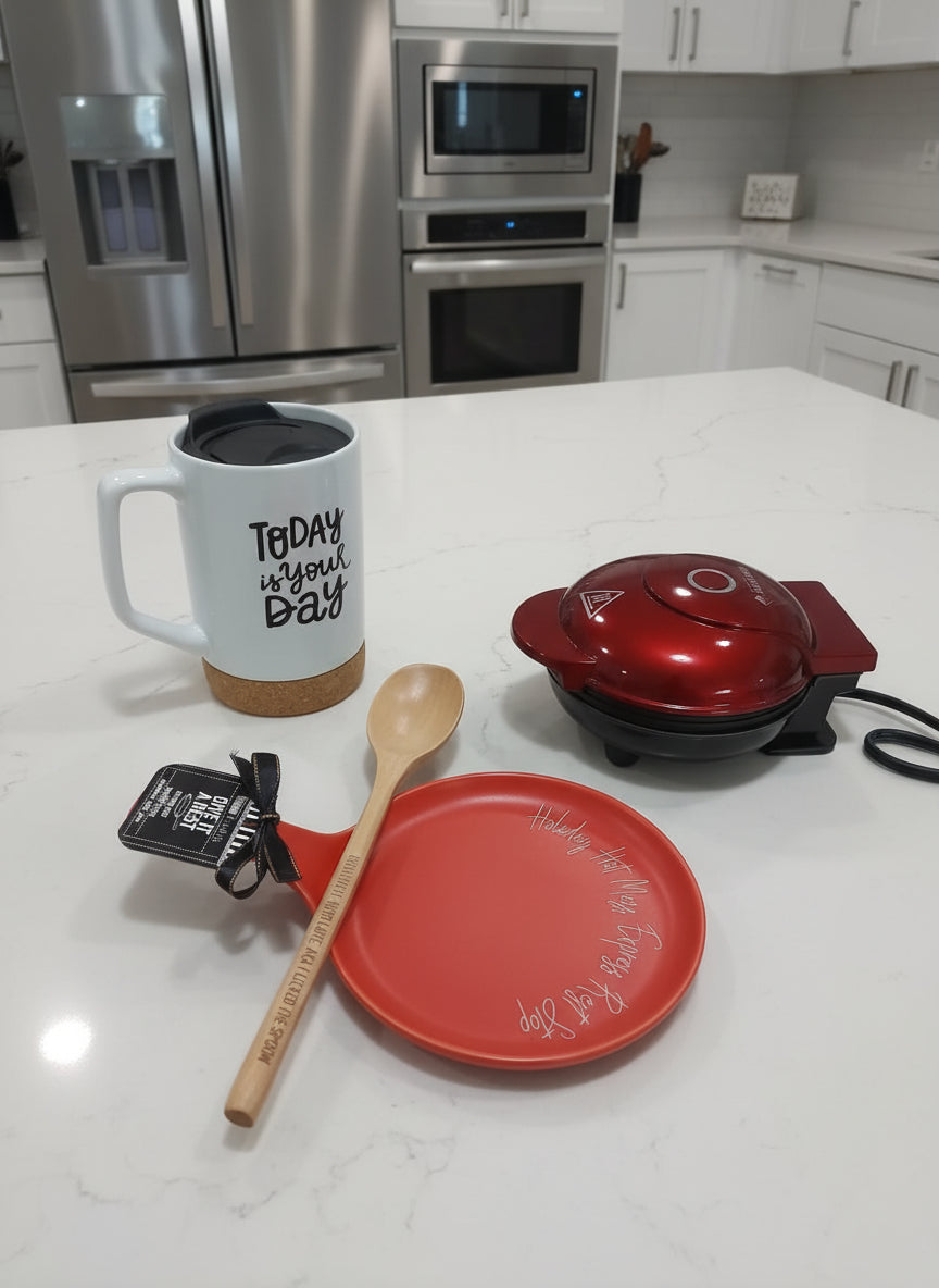 Kitchen counter with a mug, red plate, spoon, and small appliance.