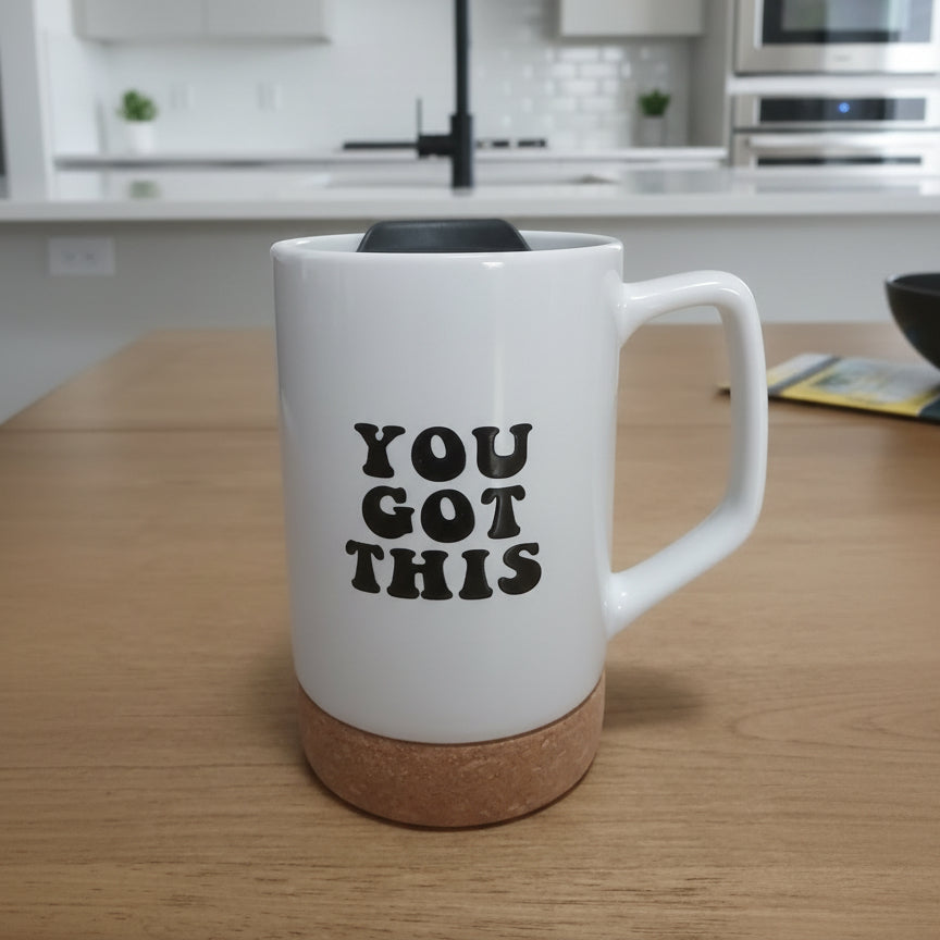 White mug with 'YOU GOT THIS' text on a wooden surface in a kitchen.