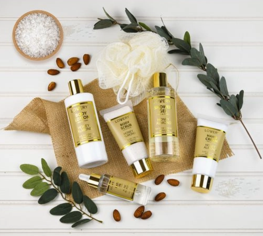 Set of skincare products with gold and white packaging on a wooden surface with greenery.