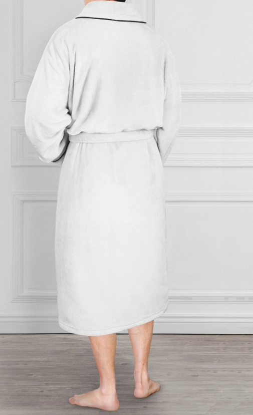 Person wearing a white robe standing in a room with a wooden floor and white walls.