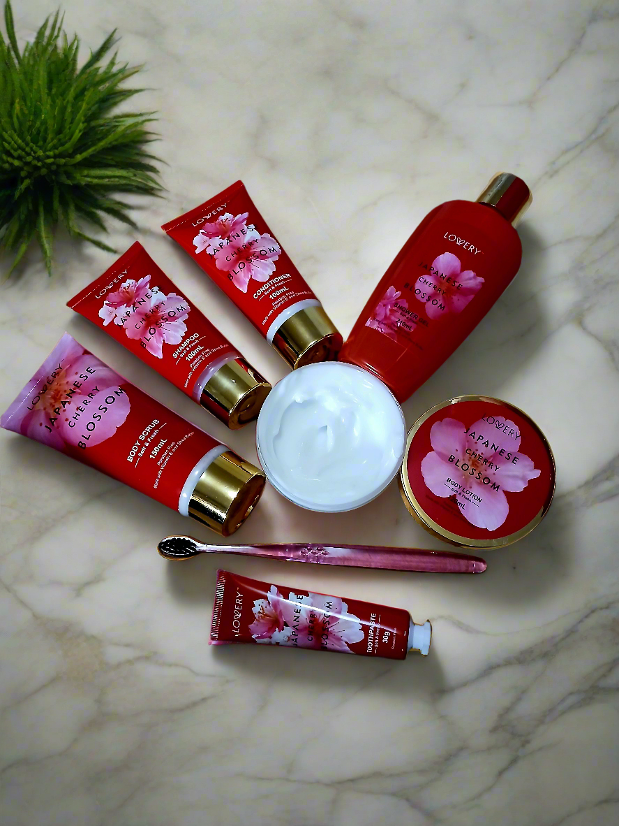 Set of Cherry Blossom-themed skincare products on a marble surface with a plant in the corner.
