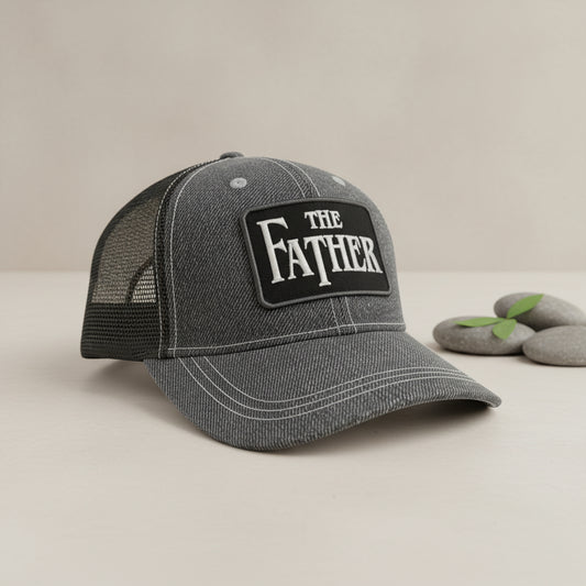 Gray cap with 'The Father' text on a wooden surface