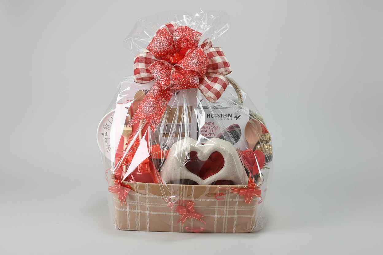 Gift basket with a red bow on a wooden table in a kitchen.