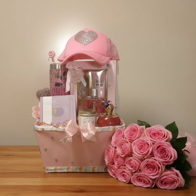 Gift basket with pink hat, bottles, and other items on a pink background