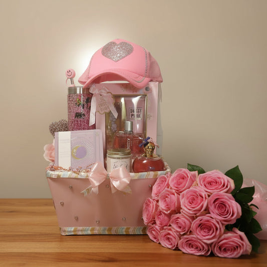Gift basket with pink hat, bottles, and other items on a pink background