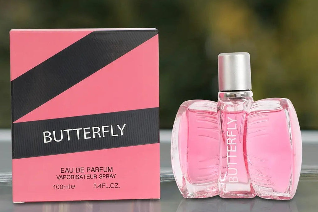 Pink Butterfly Eau de Parfum spray bottle and its matching pink and black box, displayed on a reflective surface with a blurred green background and the text 'GIFTING MADE EASY' at the bottom.