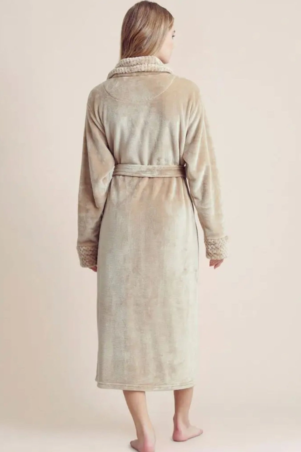 Person wearing a beige robe against a plain background